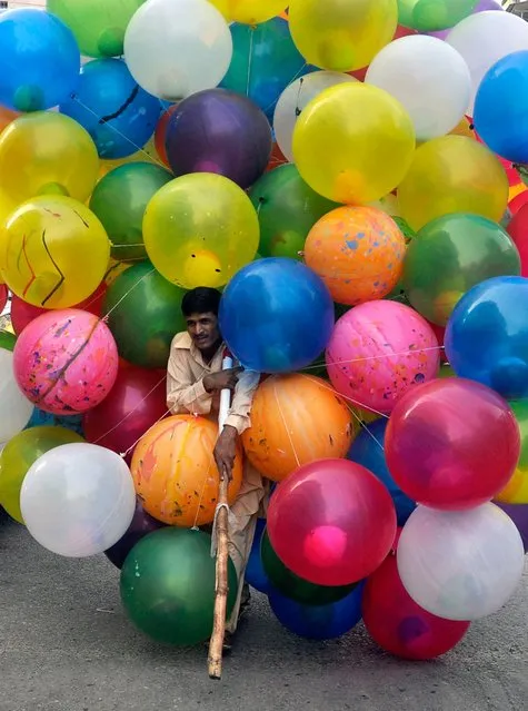 A Pakistani man sells colorful balloons as he waits for customers during the Eid al-Fitr celebrations, in Karachi, Pakistan, July 29, 2014. Muslims all over the world are celebrating their biggest religious festival, Eid al-Fitr, which marks the end of the holy fasting month of Ramadan. (Photo by Shahzaib Akber/EPA)