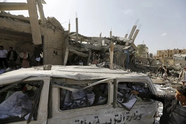 A Houthi militant checks documents loaded on a van destroyed by Saudi-air strikes on the offices of the education ministry's workers union in Yemen's northwestern city of Amran August 19, 2015. (Photo by Khaled Abdullah/Reuters)