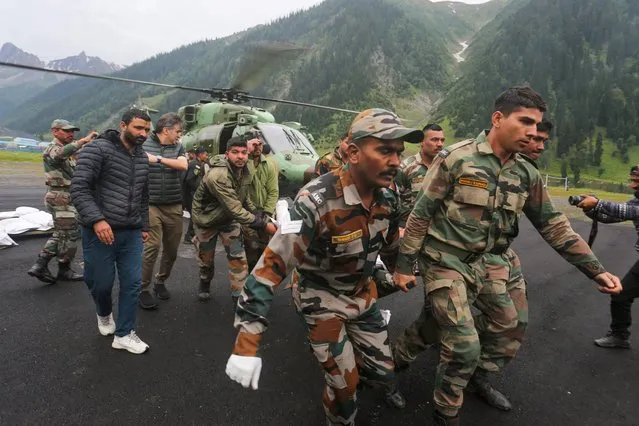 Soldiers carry a flash flood affected victim during the Amarnath pilgrimage near Baltal base camp in Kashmir on July 9, 2022. Sixteen people were killed in Indian-administered Kashmir, with rescuers searching for dozens more missing, after flash floods swept away hundreds of tents near a popular Hindu pilgrimage site, officials said on July 9. (Photo by Abid Bhat/AFP Photo)