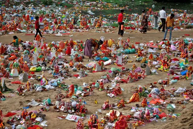 A woman collects recyclable items from the idols of Hindu goddess Dashama, left by devotees on the banks of the river Sabarmati a day after the “Dashama” festival, in Ahmedabad, India on August 7, 2022. (Photo by Amit Dave/Reuters)