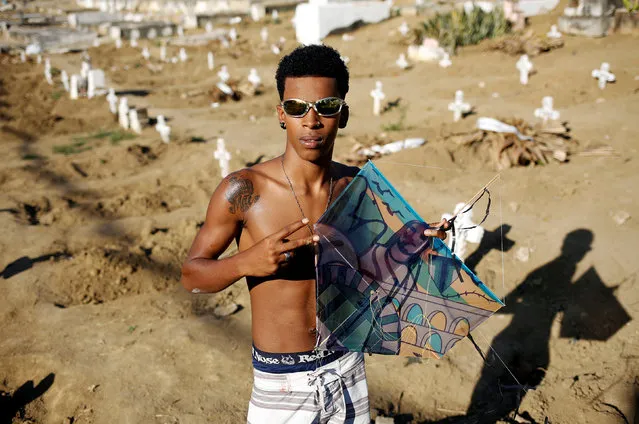 Bala Jr, 17, poses with his kite in a cemetery in the Vila Operaria Favela of Rio de Janeiro, Brazil, July 10, 2016. (Photo by Nacho Doce/Reuters)