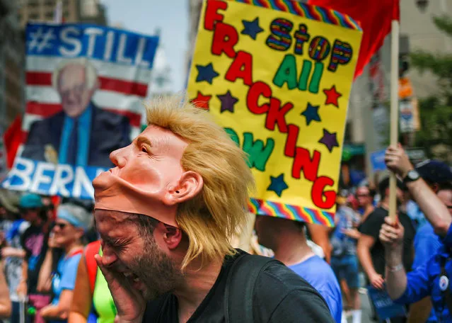 A man wearing a Donald Trump mask wipes sweat from his face as demonstrators from various groups, including supporters of U.S. Senator Bernie Sanders, take part in a protest march on the first day of the 2016 Democratic National Convention in Philadelphia, Pennsylvania, U.S. July 25, 2016. (Photo by Adrees Latif/Reuters)