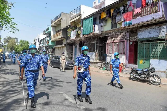 Security personnel wearing facemasks patrol on a deserted street during a government-imposed nationwide lockdown as a preventive measure against the COVID-19 coronavirus, in Ahmedabad on April 11, 2020. (Photo by Sam Panthaky/AFP Photo)