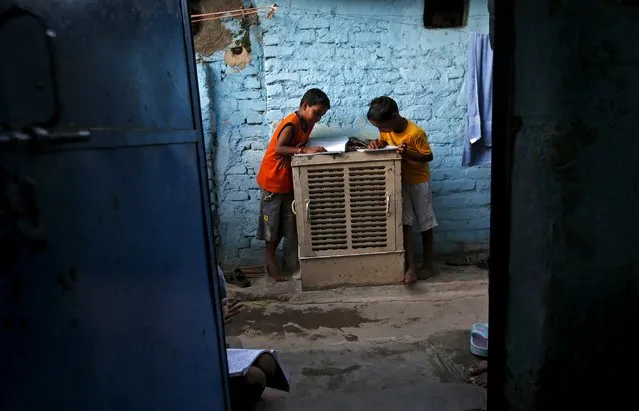 Boys use an air cooler as a table as they study outside their home during a power-cut in New Delhi, India, August 31, 2015. (Photo by Adnan Abidi/Reuters)
