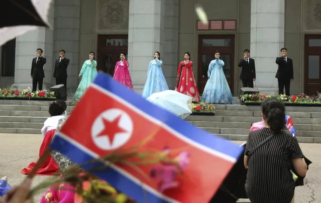 People enjoy a singing performance, waving their national flag in the plaza of Pyongyang Grand Theatre in Pyongyang, North Korea, Wednesday, July 27, 2022, on the occasion of the 69th anniversary of the end of the Korean War. The country celebrates as the day of “victory in the fatherland liberation war”. (Photo by Cha Song Ho/AP Photo)