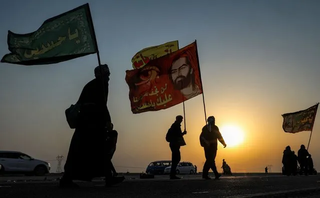 Shiite Muslim pilgrims march with flags en route to Karbala from Nasiriyah in Iraq's southern Dhi Qar province on September 5, 2022, ahead of the holiday of Arbaeen. (Photo by Asaad Niazi/AFP Photo)