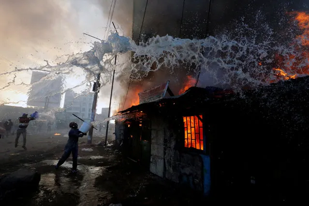 People try to put out a fire at properties set ablaze by rioters in Kawangware slums in Nairobi, Kenya October 27, 2017. (Photo by Thomas Mukoya/Reuters)