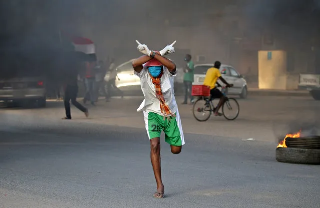 A Sudanese protester clad in mask and latex gloves runs during a demonstration marking the first anniversary of a raid on an anti-government sit-in, in the Riyadh district in the east of the capital Khartoum on June 3, 2020. Scores of protesters were killed when armed men in military fatigues stormed the sprawling encampment outside Khartoum's army headquarters on June 3 last year. (Photo by Ashraf Shazly/AFP Photo)