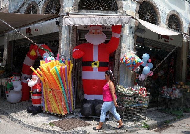 A woman passes by an inflatable Santa Claus at the Saara market in Rio de Janeiro, Brazil on December 1, 2023. (Photo by Pilar Olivares/Reuters)