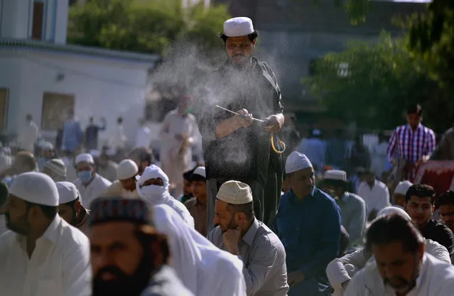 A Pakistani sprays disinfectant among worshipers attending an Eid al-Fitr prayer at a ground in Rawalpindi, Pakistan, Sunday, May 24, 2020. Millions of Muslims across the world are marking a muted and gloomy holiday of Eid al-Fitr, the end of the fasting month of Ramadan – a usually joyous three-day celebration that has been significantly toned down as coronavirus cases soar. (Photo by Anjum Naveed/AP Photo)