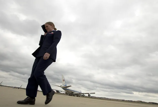 2nd Lt. Jacqueline Alequin covers her face from the jets blast as Air Force One, with President Barack Obama aboard, departs from Andrews Air Force Base, Md., Friday, October 3, 2014. Obama is traveling to Princeton, Ind., to speak about the economy as part of Manufacturing Day. US employers added 248,000 jobs in September, a burst of hiring that helped drive down the unemployment rate to 5.9 percent, the lowest since July 2008. (Photo by Jose Luis Magana/AP Photo)