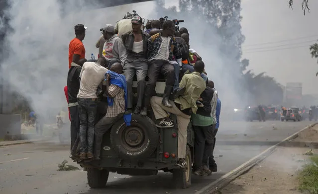Kenyan opposition supporters follow leader Raila Odinga of the National Super Alliance (NASA) upon his return in Nairobi, Kenya, Friday, November17, 2017. Kenyan police have used tear gas and water cannons to disperse supporters of opposition leader Raila Odinga who are trying to gather near the country's main airport and Uhuru park to welcome him back from an overseas trip. The supporters are responding to a call to welcome Odinga after speaking engagements in the United States and Britain over Kenya's political turmoil following a court-nullified presidential election and the fresh vote last month. (Photo by Brian Inganga/AP Photo)