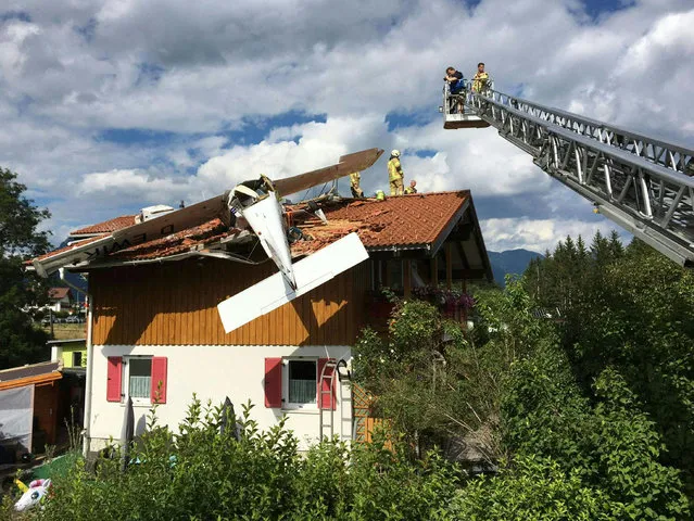 A photo taken on July 31, 2022 shows firefighters standing on a rooftop of a house after a small aircraft crashed onto it, in Hoefen, near Reutte, Austria. Two injured people were recovered from the accident site. (Photo by Zoom.Tirol/APA via AFP Photo)