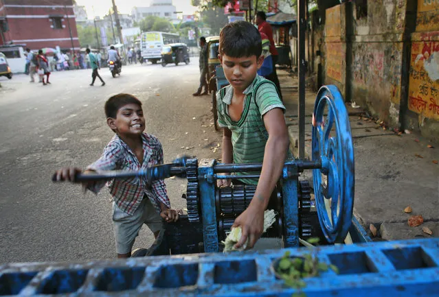 Ravi, 8, left, and Guddu, 12, extract sugarcane juice, in Gauhati, India, Friday, October 10, 2014. Malala Yousafzai of Pakistan and Kailash Satyarthi of India won the Nobel Peace Prize on Friday, Oct. 10, 2014, for risking their lives to fight for children's rights. (Photo by Anupam Nath/AP Photo)