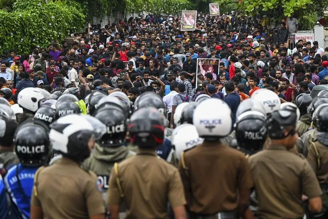 Policemen stand guard as protestors take part in an anti-government demonstration by the university students demanding the release of their leaders, in Colombo on October 18, 2022. (Photo by Ishara S. Kodikara/AFP Photo)