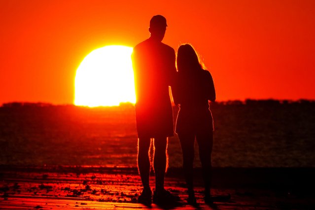 A couple are silhouetted by the rising sun as they stop to watch the sunrise at Wild Dunes beach, May 31, 2025 in Isle of Palms, South Carolina. (Photo by Richard Ellis/Alamy Live News)