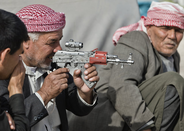 Syrian Kurdish refugee men from the Kobani area, play with a toy weapon at a camp in Suruc, on the Turkey-Syria border Thursday, November 13, 2014. Kobani, also known as Ayn Arab, and its surrounding areas, has been under assault by extremists of the Islamic State group since mid-September and is being defended by Kurdish fighters. (Photo by Vadim Ghirda/AP Photo)