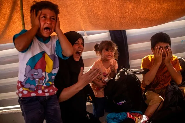 A migrant woman and children react after police threw tear gas during clashes near the city Mytilene on the Greek island of Lesbos, on September 12, 2020, a few days after a fire destroyed the Moria refugee camp. Police on the Greek island of Lesbos fired tear gas at migrants on September 12 who threw stones during a protest to demand shelter after the local camp of Moria burned down, an AFP photographer said. (Photo by Angelos Tzortzinis/AFP Photo)