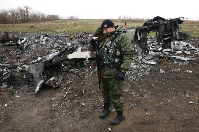 A pro-Russian separatist stands guard in front of debris at the site where the downed Malaysia Airlines flight MH17 crashed, near the village of Hrabove (Grabovo) in Donetsk region, eastern Ukraine November 16, 2014. (Photo by Maxim Zmeyev/Reuters)