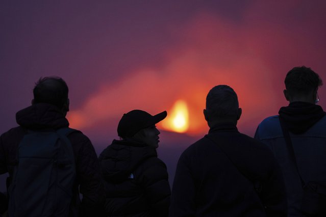 A group of visitors gather on a hill a few kilometers away to watch the two active craters, after a volcanic eruption around 6km north of Grindavik on the Reykjanes Peninsula, in Iceland, Saturday, July 19, 2025. (Photo by Marco di Marco/AP Photo)