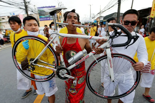 A devotee of the Chinese Samkong Shrine walks with a bike pierced on his mouth during a procession celebrating the annual vegetarian festival in Phuket, Thailand October 4, 2016. (Photo by Jorge Silva/Reuters)