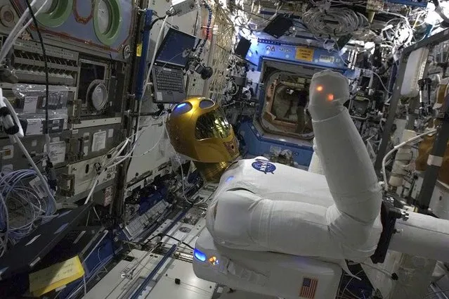 NASA's Robonaut 2, the first humanoid robot in space, is put through its paces aboard the International Space Station, as seen in a photo sent by Canadian astronaut Chris Hadfield on March 18, 2013. Robonaut was designed with the intention of eventually taking over tasks deemed too dangerous or mundane for astronauts. “It will be even more interesting when his legs are installed”, Hadfield said. (Photo by Chris Hadfield/CSA via Reuters)