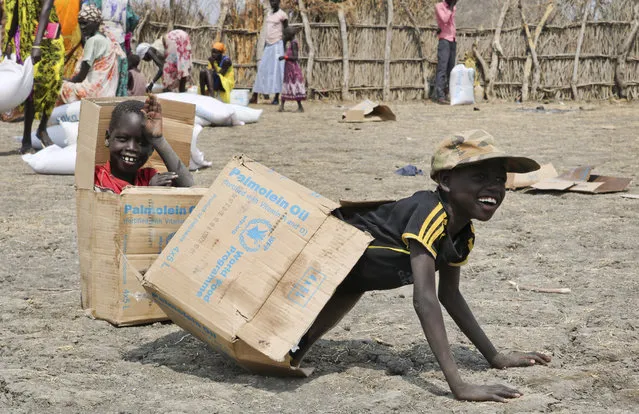 In this photo taken Saturday, January 20, 2018, children play in empty cardboard boxes during a food distribution by Oxfam outside Akobo town, one of the last rebel-held strongholds in South Sudan. (Photo by Sam Mednick/AP Photo)