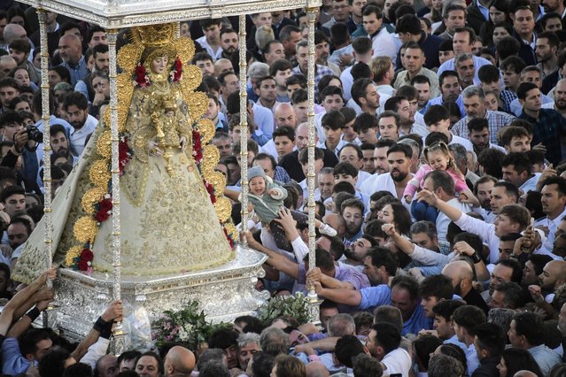 Pilgrims gather around the effigy of the Rocio Virgin during the annual pilgrimage in El Rocio village, on May 20, 2024. El Rocio pilgrimage, the largest in Spain, gathers hundreds of thousands of devotees in traditional outfits converging in a burst of colour as they make their way on horseback and on board decorated carriages across the Andalusian countryside. (Photo by Cristina Quicler/AFP Photo)