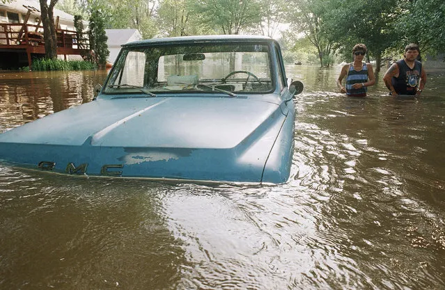 Shannon Rennert, of Moline, Ill., left, and Jim Sappington, of East Lawn, Ill., walk down a flooded street, Tuesday, June 29, 1993, Pleasant Valley, Iowa. Water from the Mississippi River is flooding many of the homes along its banks. Rennert and Sappington were in Pleasant valley to help Rennerts brother move his belongings. (Photo by John Gaps III/AP Photo)