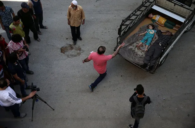 Syrian director Humam Husari (wearing pink) directs actors while cameraman Sami al-Shami (wearing white) operates a camera as they film a scene in the rebel-held besieged town of Zamalka, in the Damascus suburbs, Syria September 19, 2016. (Photo by Bassam Khabieh/Reuters)