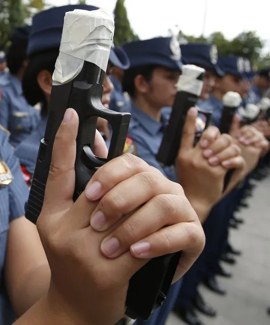 Female members of the Philippine National Police (PNP) hold their service pistols that are covered with tape during the sealing of the muzzles of firearms at the National Capital Region Police Office in Taguig, Metro Manila, December 22, 2014. (Photo by Erik De Castro/Reuters)