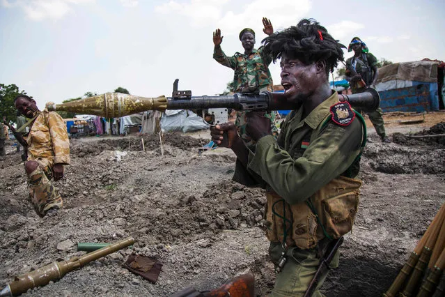 Soldiers of the Sudan People Liberation Army (SPLA) celebrate while standing in trenches in Lelo, outside Malakal, northern South Sudan, on October 16, 2016. Heavy fighting broke out on Ocotober 14 between SPLA (Government) and opposition forces in Wajwok and Lalo villages, outside Malakal. SPLA commanders claim they succeeded to keep their positions and assure their forces just responded “on self defence”. (Photo by Albert Gonzalez Farran/AFP Photo)