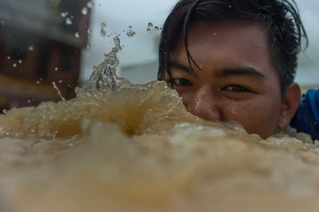 A boy looks on as he swims in floodwaters in Kota Bahru on December 28, 2014. (Photo by Mohd Rasfan/AFP Photo)