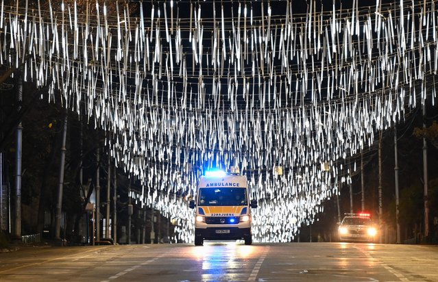 An ambulance moves on a street under light decorations for the upcoming Christmas and New Year holidays during a night-time curfew imposed by the government amid the ongoing coronavirus disease pandemic in Tbilisi late on December 17, 2020. (Photo by Vano Shlamov/AFP Photo)
