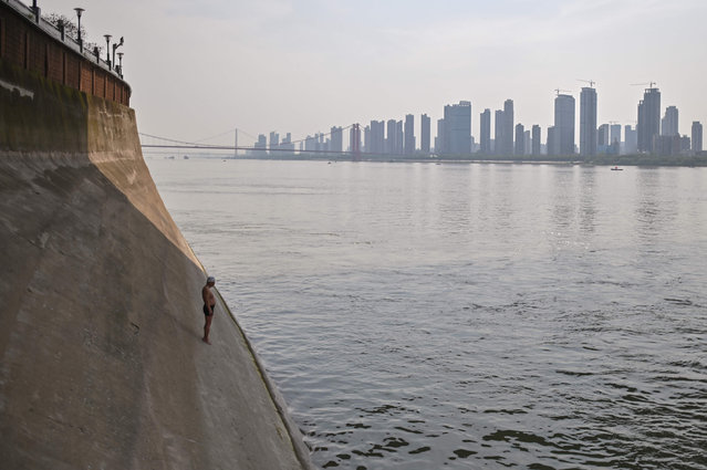 A man prepares to jump into the Yangtze river in Wuhan, China's central Hubei province on April 16, 2020. China has largely brought the coronavirus under control within its borders since the outbreak first emerged in the city of Wuhan late last year. (Photo by Hector Retamal/AFP Photo)