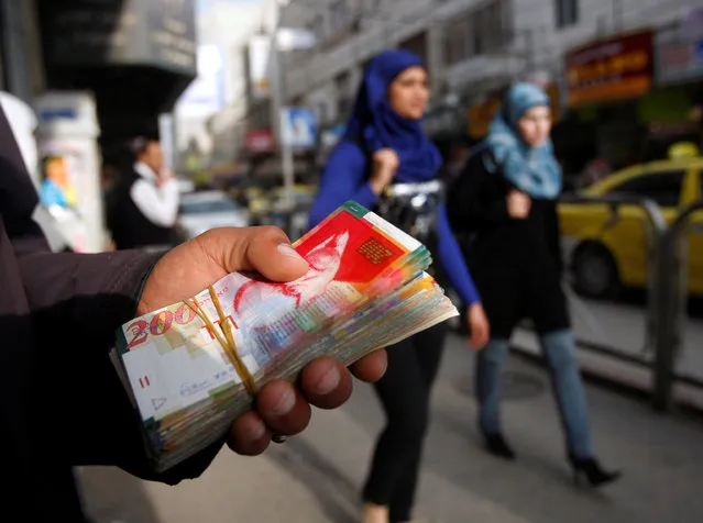 Palestinian women walk past a money changer in the West Bank city of Ramallah February 16, 2010. (Photo by Mohamad Torokman/Reuters)