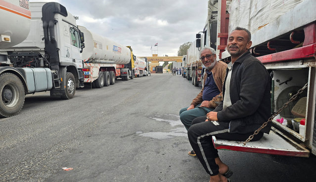 Egyptian volunteers sit next to trucks loaded with humanitarian aid and fuel line up at the crossing into the Gaza Strip at the Rafah border on the Egypt side, amid a ceasefire between Israel and Hamas in Gaza, in Rafah, Egypt, on October 19, 2025. (Photo by Reuters/Stringer)