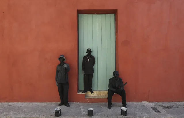 Street performers act as statues outside a home in the historical center of Cartagena, Colombia, Friday, October 28, 2016. Cartagena is hosting the 25th Ibero-American Summit, an annual meeting of heads of state from Latin America and the Iberian Peninsula. (Photo by Fernando Vergara/AP Photo)