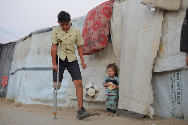 Thirteen-year-old Mohammad Tareq Salih plays football with a crutch after losing one leg when the school where he had sought refuge during the early days of the war was hit, in Nuseirat, Gaza on November 11, 2025. Following the attack, doctors were forced to amputate the lower part of his leg. However, medical shortages led to an infection in the wound, and his leg had to be amputated again, this time above the previous point. Mohammad now faces a long and painful recovery, battling both the physical suffering and the deep psychological trauma brought on by the war. (Photo by Hassan Jedi/Anadolu via Getty Images)