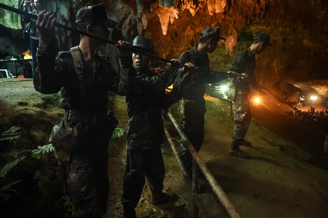 Thai soldiers relay electric cable deep into the Tham Luang cave at the Khun Nam Nang Non Forest Park in Chiang Rai on June 26, 2018 during a rescue operation for a missing children' s football team and their coach. Desperate parents led a prayer ceremony outside a flooded cave in northern Thailand where 12 children and their football coach have been trapped for days, as military rescue divers packing food rations resumed their search on June 26. (Photo by Lillian Suwanrumpha/AFP Photo)
