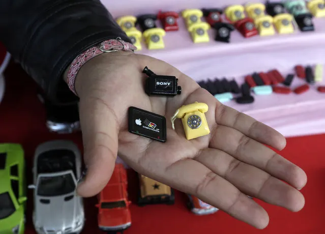A woman holds miniatures of a video camera, a tablet and a telephone during the “Alasitas” fair in La Paz January 24, 2015. (Photo by David Mercado/Reuters)