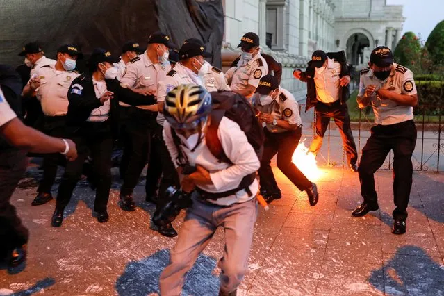 Police officers react as a molotov cocktail from demonstrators falls during a protest to demand the resignation of Guatemala's President Alejandro Giammattei in Guatemala City, Guatemala on November 28, 2020. (Photo by Luis Echeverria/Reuters)