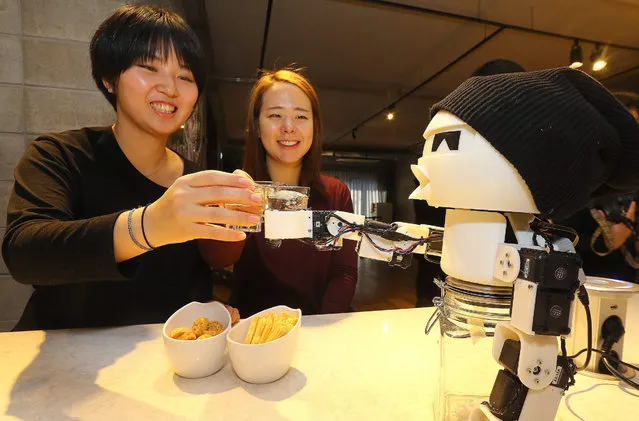 A visitor toasts with “Drinki” (R), a drinking robot, during the Robot Party event in Seoul, South Korea, 16 December 2015. Organized by a digital art museum, the Art Center Nabi, the event offers people an opportunity to form emotional connections with robots, the Yonhap news agency reported. (Photo by Yonhap/EPA)