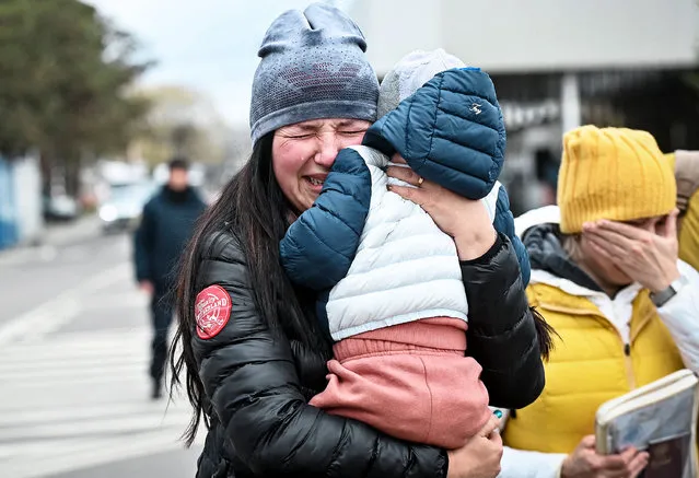 A Ukrainian refugee holding her child cries after she arrived at the Siret border crossing between Romania and Ukraine on April 18, 2022. (Photo by Daniel Mihailescu/AFP Phoot)