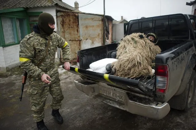 A Ukrainian servicemen, dressed in camouflage, lies in a vehicle while his comrade locks the tailboard in a village near Mariupol, a city on the Sea of Azov, January 26, 2015. (Photo by Maksim Levin/Reuters)
