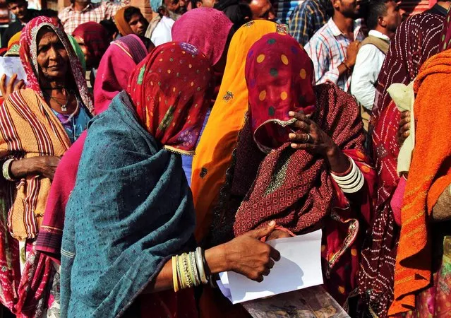 Women check their documents as they queue outside a bank to exchange and deposit their old high denomination banknotes in Gagwana village in the desert Indian state of Rajasthan, India, November 16, 2016. (Photo by Himanshu Sharma/Reuters)