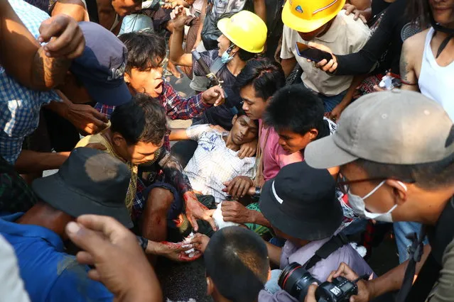 Anti-coup protesters surround an injured man in Hlaing Thar Yartownship in Yangon, Myanmar Sunday, March 14, 2021. A number of people were shot dead during protests in Myanmar's largest city on Sunday, as security forces continued their violent crackdown against dissent following last month's military coup. (Photo by AP Photo/Stringer)