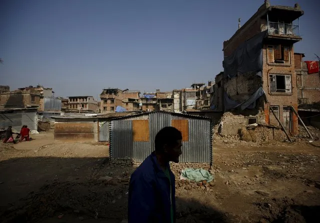 An earthquake victim is silhouetted as he stands in front of temporary shelters built near damaged houses after the earthquake which happened earlier this year, in Bhaktapur, Nepal November 19, 2015. (Photo by Navesh Chitrakar/Reuters)