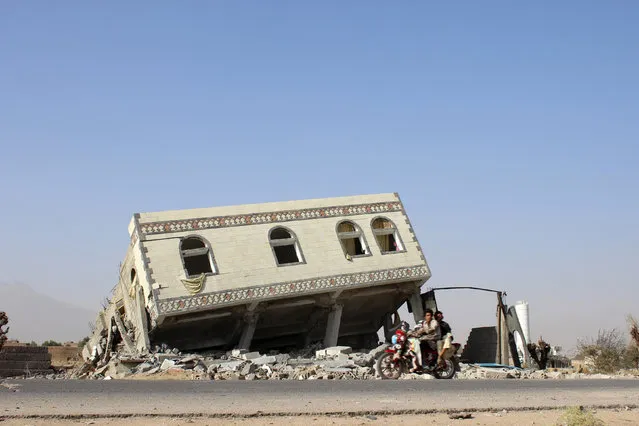 People ride a motorbike past a collapsed building after it was hit by a Saudi-led air strike in the northwestern city of Saada, Yemen November 26, 2016. (Photo by Naif Rahma/Reuters)