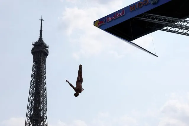 An athlete dives off the Port Debilly on the banks of the Seine river in front of the Eiffel tower during a training ahead of the competition Red Bull Cliff Diving World in Paris, France on June 16, 2023. (Photo by Stephanie Lecocq/Reuters)